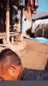 a man is standing in front of a house with clothes hanging on a pole .
