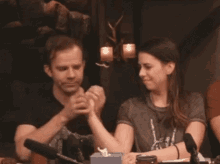 a man and a woman are sitting at a table with microphones in a room .
