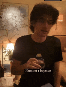 a man in a black shirt holds a glass and says number 1 boyssss