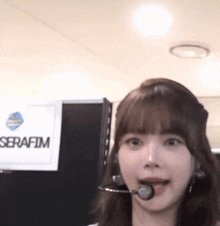 a woman wearing a headset is standing in front of a sign that says serafim .