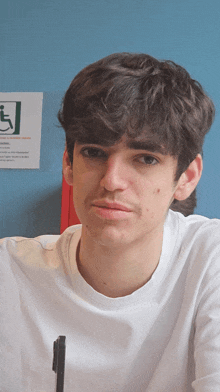 a young man sitting in front of a blue wall with a sign on it that says handicap accessible