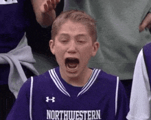 a boy wearing a purple northwestern jersey screams