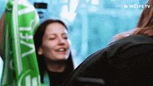 a woman wearing a green scarf that says wolfe tv