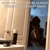 a person standing in a doorway with the caption when you say you 're almost there but you are at home