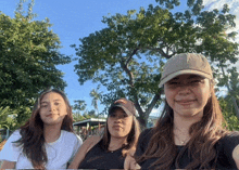 three women posing for a picture with one wearing a hat that says hawaii on it