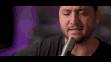 a man with a beard is singing into a microphone .