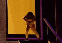 a woman is dancing on a stage with her arms outstretched in front of a yellow wall .