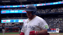 a baseball player wearing a blue jays jersey stands on the field