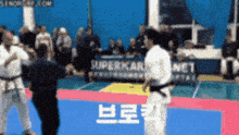 a karate match is being played in front of a superkarl net sign