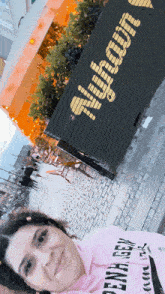 a woman taking a selfie in front of a sign that says ' a ' on it