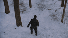 a man is running through the snow while another man watches