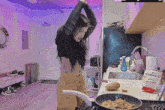 a woman is cooking in a kitchen with a bag of hoomajii sitting on the counter