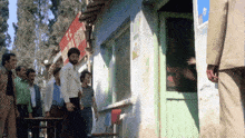 a group of people standing outside of a building with a sign that says ' t.c. ' on it