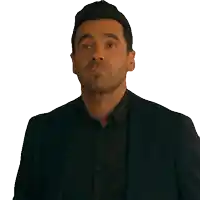 a man in a suit and black shirt making a face