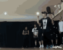 a group of people are standing in a dance studio and one of them is wearing a shirt with the number 81 on it .