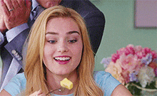 a woman is eating a piece of butter with a fork and smiling .