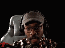 a man wearing headphones and a hat holds his arms up in the air