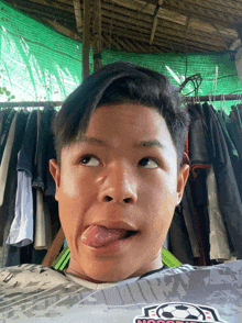 a young boy wearing a shirt that says soccer sticking out his tongue