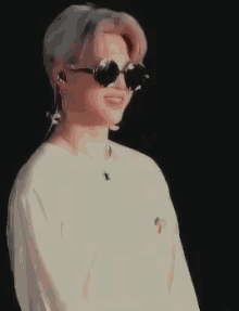 a person wearing sunglasses and a white shirt with the word mombo on the bottom right
