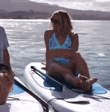 a woman in a bikini sits on a surfboard in the ocean