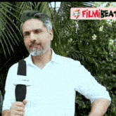 a man in a white shirt is holding a microphone in front of a sign that says filmbeat