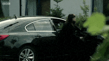 a woman is getting out of a car that says bbc
