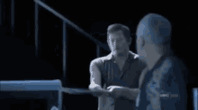 a man is laying on a bed in a dark room holding a stick in his hand .