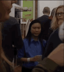 a woman in a blue shirt is standing in a crowded room