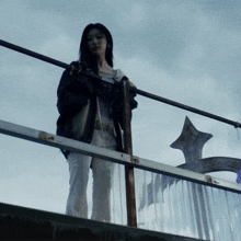 a woman standing on a railing with a cross in the back