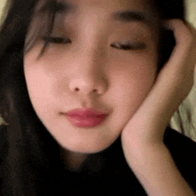 a close up of a woman 's face with her hand on her forehead .