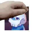 a hand is holding a picture of a cartoon character with a skull on it .