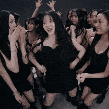 a group of women in black dresses are dancing together