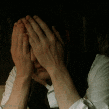 a person covering their face with their hands with a dark background and a watermark that says ' otrip.com '