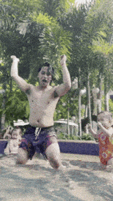a shirtless man is kneeling in a swimming pool with his arms in the air