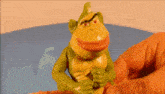 a person is holding a toy that looks like a frog with a red mouth .