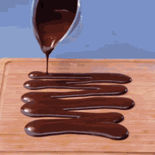 chocolate is being poured on a wooden surface in a row