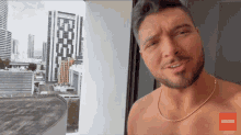 a shirtless man stands in front of a window with a subscribe button on the bottom