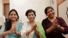 three women are clapping their hands in front of a white wall