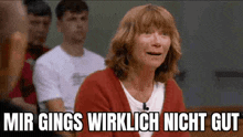 a woman in a red sweater is sitting in front of a group of people and says mir ging 's wirklich nicht gut