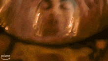 a close up of a person 's face behind a glass with a prime arrow in the corner .