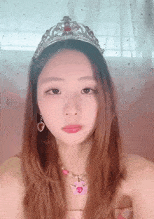 a woman wearing a tiara and a necklace with a heart shaped pendant