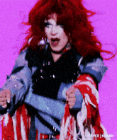 a woman with red hair and a denim jacket is dancing on a purple background .