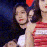 a group of women are standing next to each other in a room . one of the women is wearing a red striped shirt .