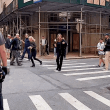 a woman crosses a street in front of a building with a one way sign