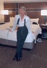 a woman in a white shirt and black pants is sitting on a bed in a hotel room