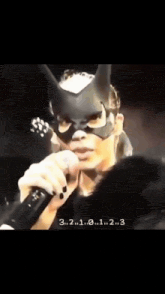 a woman wearing a cat mask is singing into a microphone ..
