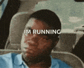 a man is sitting in the back seat of a car with the words `` im running '' written on his face .