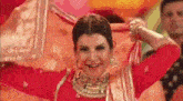 a woman in a red dress is smiling and dancing with her hands in the air .