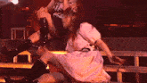 a girl in a pink dress is sitting on a stage with another girl
