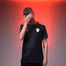 a man wearing a shirt that says syner covering his face with his hand